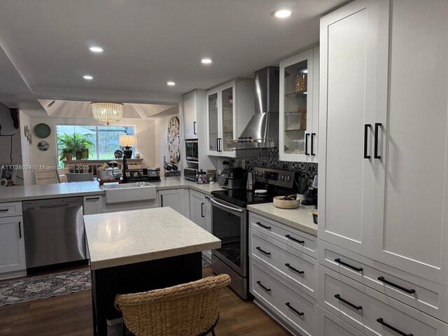 kitchen with white cabinetry, appliances with stainless steel finishes, sink, and wall chimney range hood