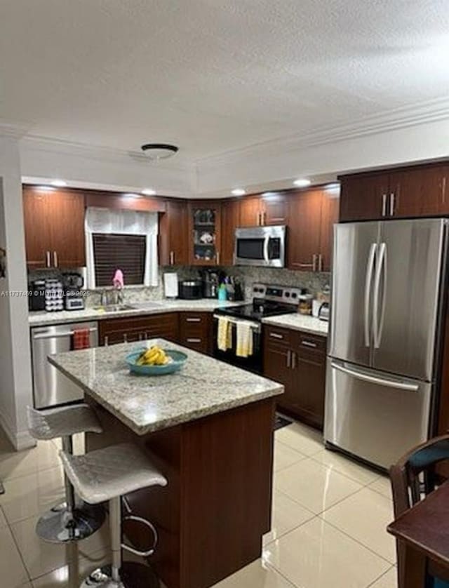 kitchen featuring light tile patterned floors, sink, stainless steel appliances, tasteful backsplash, and a kitchen island