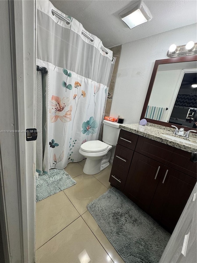 bathroom featuring vanity, toilet, tile patterned flooring, and a textured ceiling