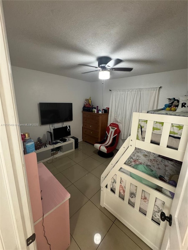 bedroom featuring ceiling fan, tile patterned floors, and a textured ceiling