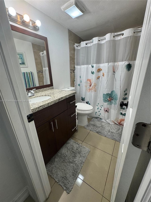 bathroom featuring tile patterned flooring, vanity, toilet, a textured ceiling, and a shower with shower curtain