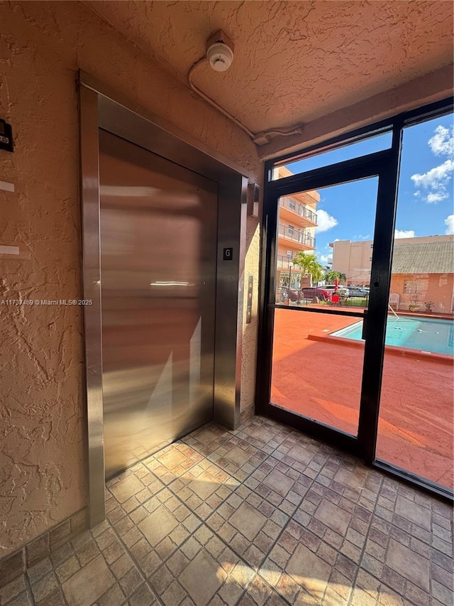 doorway with elevator and a textured ceiling