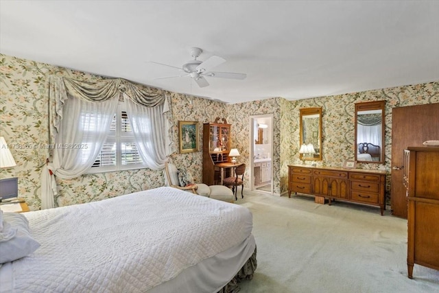 bedroom with connected bathroom, light colored carpet, and ceiling fan