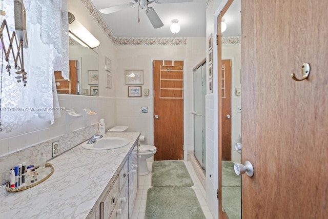 bathroom with tile walls, vanity, tile patterned floors, toilet, and walk in shower