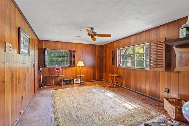 spare room featuring a wealth of natural light, wooden walls, and ceiling fan