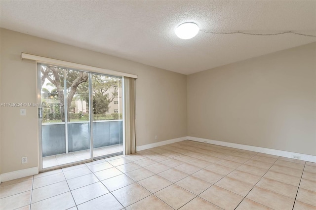 spare room featuring a textured ceiling, light tile patterned flooring, and baseboards