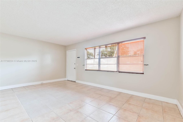 spare room with a textured ceiling and baseboards