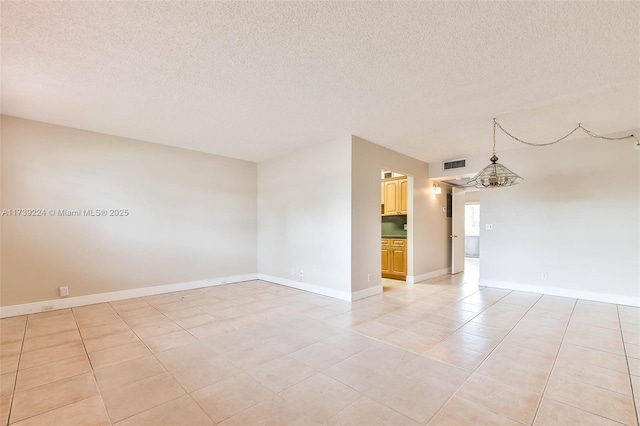 spare room with visible vents, baseboards, and a textured ceiling