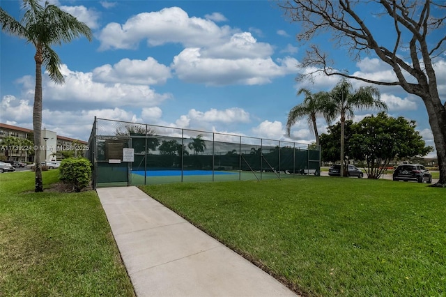 surrounding community featuring a tennis court, a gate, fence, and a lawn