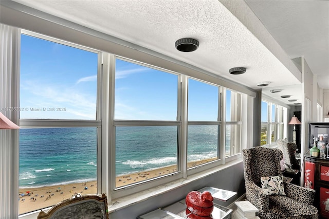 sunroom / solarium featuring a water view and a view of the beach