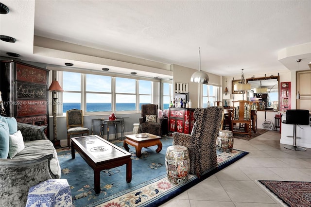 tiled living room featuring a textured ceiling and a water view