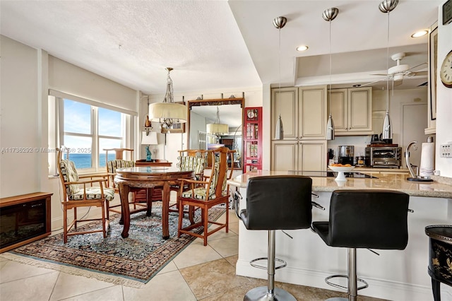 kitchen with pendant lighting, ceiling fan, a kitchen breakfast bar, a water view, and light stone counters