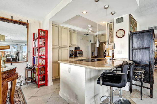 kitchen featuring stainless steel fridge, a kitchen bar, hanging light fixtures, kitchen peninsula, and cream cabinetry