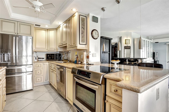 kitchen with sink, light stone counters, hanging light fixtures, appliances with stainless steel finishes, and a tray ceiling