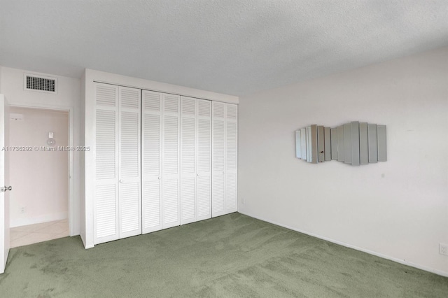 unfurnished bedroom with dark colored carpet, a textured ceiling, and a closet