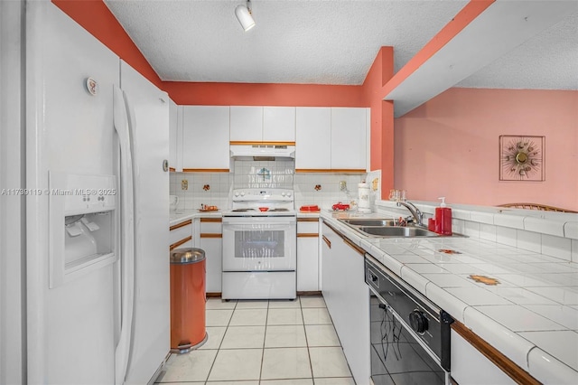 kitchen with light tile patterned flooring, sink, tile countertops, white appliances, and white cabinets