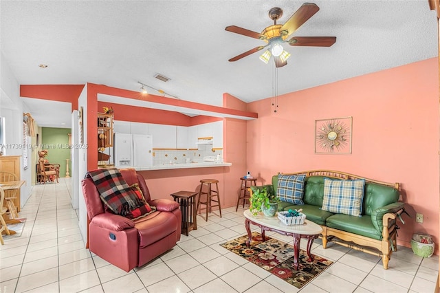 living room with vaulted ceiling, light tile patterned floors, ceiling fan, and a textured ceiling