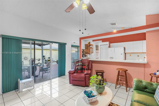 tiled living room with ceiling fan, lofted ceiling, and a textured ceiling