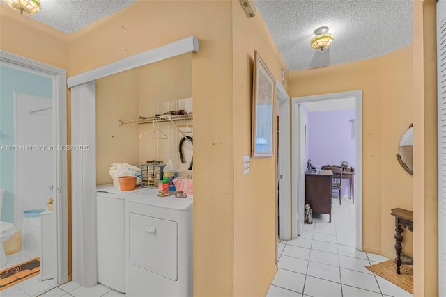 washroom with separate washer and dryer, light tile patterned floors, and a textured ceiling