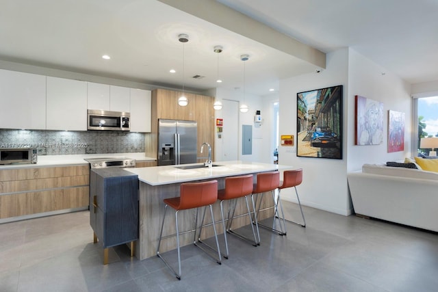 kitchen with decorative light fixtures, white cabinetry, sink, a kitchen island with sink, and stainless steel appliances