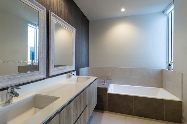 bathroom featuring tile patterned flooring, vanity, and tiled bath