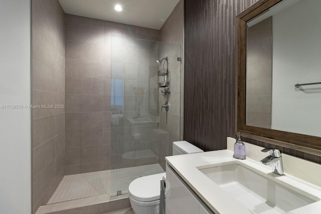 bathroom featuring vanity, toilet, and a tile shower