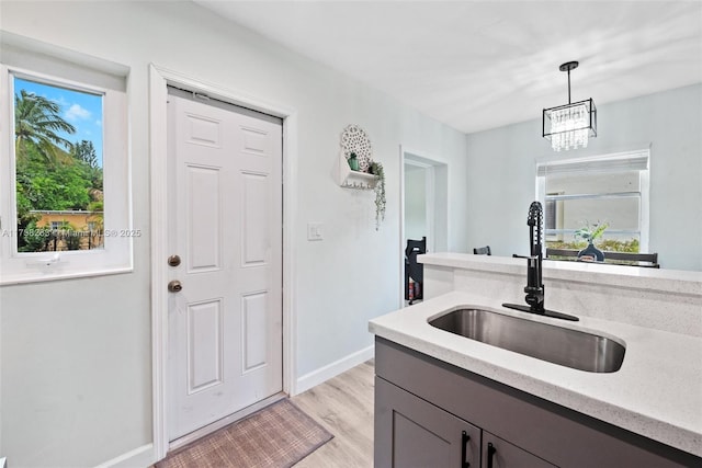 kitchen featuring a healthy amount of sunlight, light hardwood / wood-style floors, sink, and hanging light fixtures