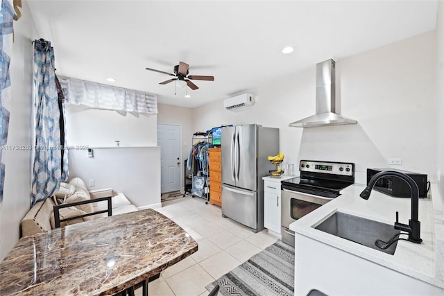 kitchen featuring light tile patterned flooring, sink, ceiling fan, stainless steel appliances, and wall chimney range hood