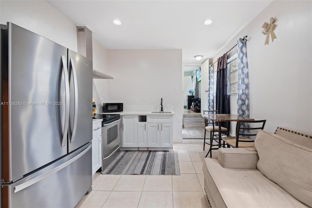 kitchen with white cabinetry, light tile patterned floors, wall chimney exhaust hood, and appliances with stainless steel finishes