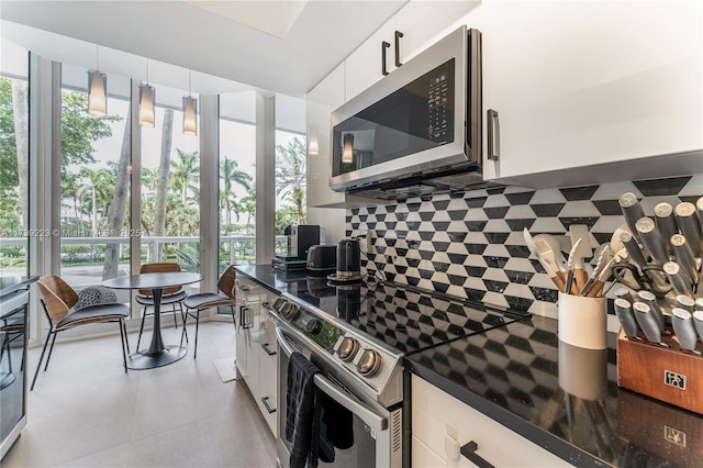 kitchen featuring tasteful backsplash, appliances with stainless steel finishes, hanging light fixtures, and white cabinets