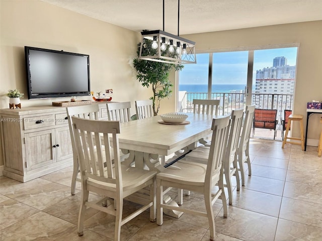 dining room featuring light tile patterned flooring, a textured ceiling, and a water view