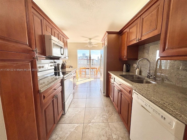 kitchen with sink, white appliances, tasteful backsplash, light stone countertops, and a textured ceiling