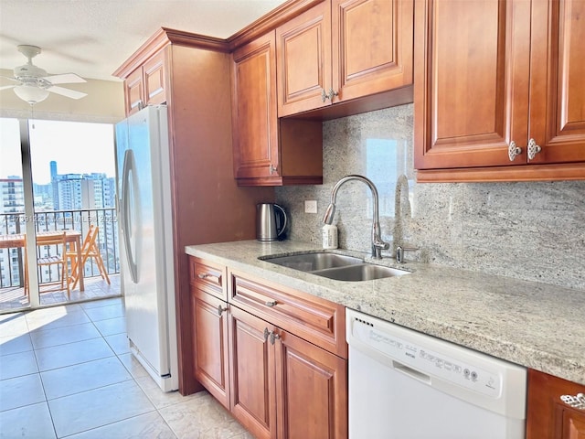 kitchen featuring sink, white appliances, light tile patterned floors, light stone counters, and tasteful backsplash