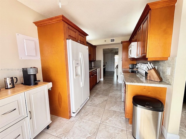 kitchen with a textured ceiling, white appliances, and decorative backsplash