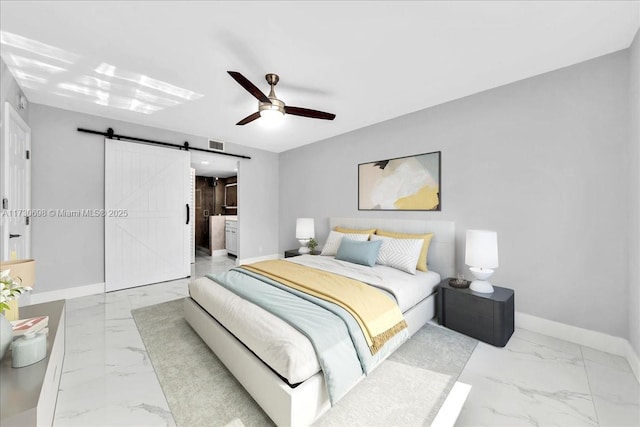 bedroom featuring a barn door, ceiling fan, and ensuite bathroom