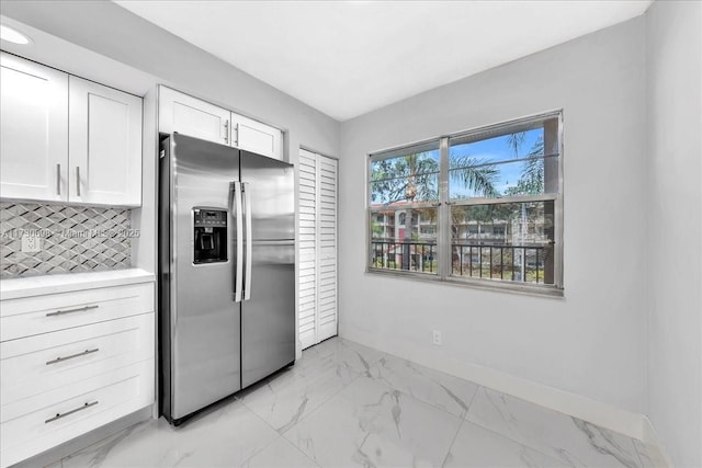 kitchen with stainless steel refrigerator with ice dispenser, white cabinets, and decorative backsplash