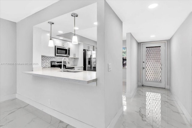 kitchen featuring sink, appliances with stainless steel finishes, kitchen peninsula, pendant lighting, and white cabinets