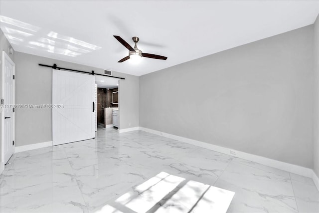 interior space featuring connected bathroom, a barn door, and ceiling fan