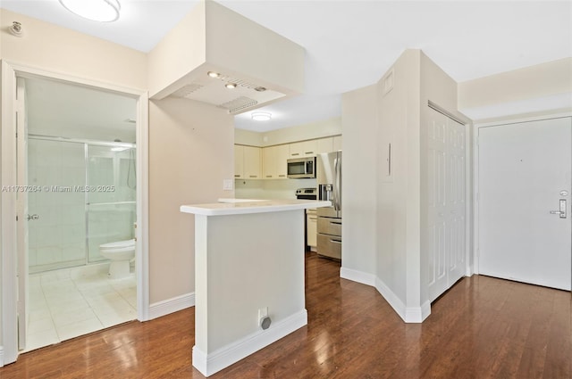 kitchen with stainless steel appliances, dark hardwood / wood-style floors, and kitchen peninsula