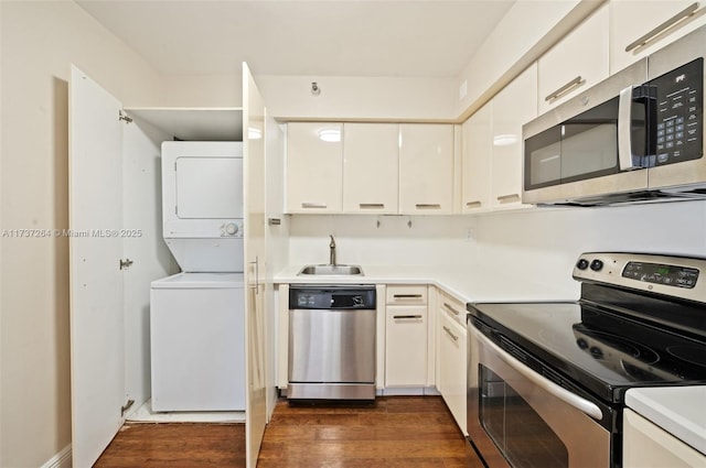 kitchen featuring stacked washer and dryer, sink, appliances with stainless steel finishes, white cabinetry, and dark hardwood / wood-style flooring