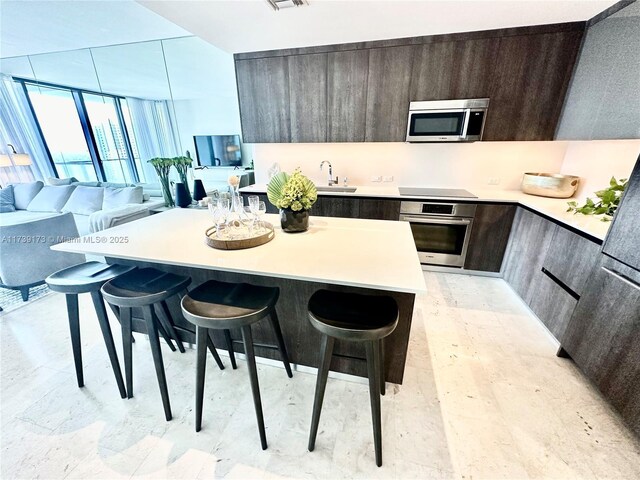 kitchen with stainless steel appliances, a center island, sink, and a kitchen bar