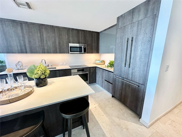 kitchen with visible vents, a kitchen bar, light countertops, stainless steel appliances, and modern cabinets