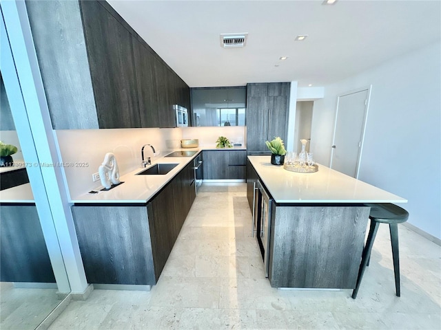 kitchen with visible vents, a sink, light countertops, stainless steel microwave, and modern cabinets