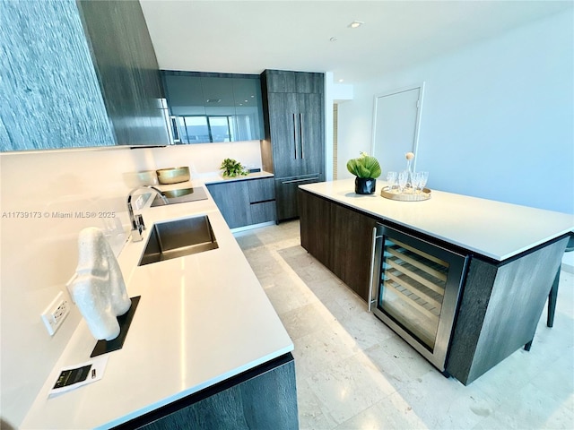 kitchen featuring a kitchen island, a sink, light countertops, wine cooler, and modern cabinets