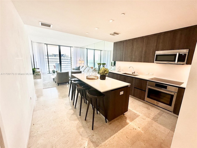 kitchen with visible vents, a sink, stainless steel appliances, a kitchen bar, and modern cabinets