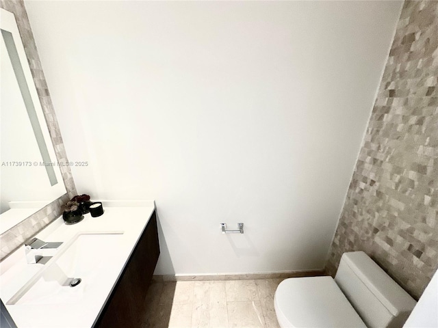 bathroom featuring toilet, vanity, and baseboards