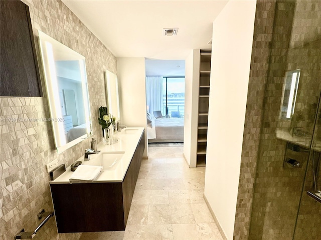 ensuite bathroom featuring visible vents, a stall shower, a sink, ensuite bath, and double vanity