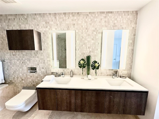 bathroom featuring double vanity, decorative backsplash, toilet, and a sink