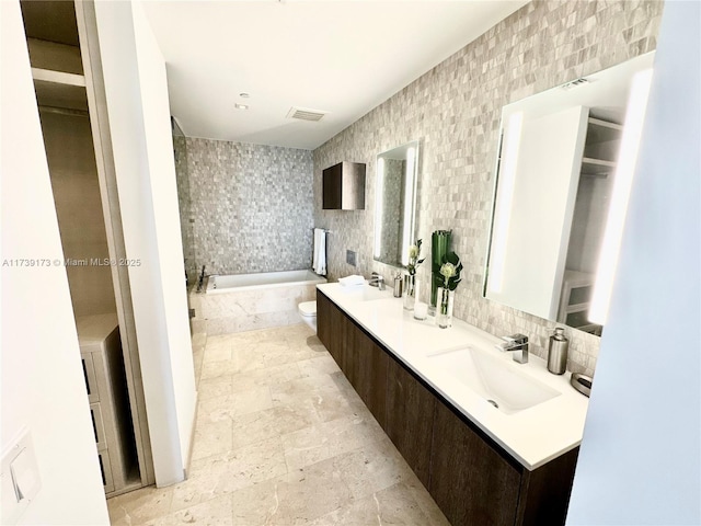 full bathroom with visible vents, decorative backsplash, a bath, tile walls, and a sink