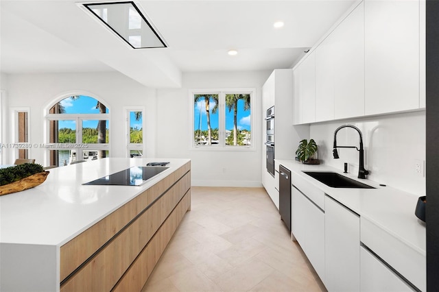 kitchen featuring white cabinetry, stainless steel appliances, a large island, and sink